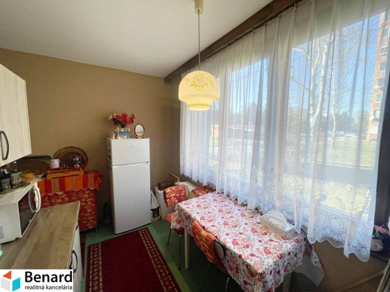 Konyha a háromszobás lakásban étkezőasztallal és nagy ablakkal.