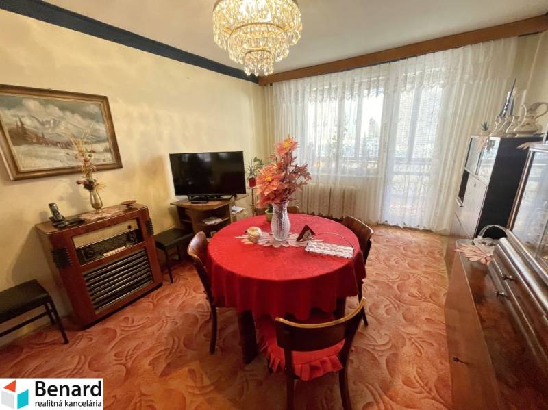 Étkező rész egy háromszobás lakásban piros terítővel és nagy ablakokkal.