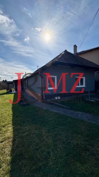 Családi ház Mýtne Ludanban, kerttel körülvéve, kék égbolttal és nappal.