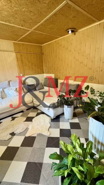 Családi ház belső tere sarokkanapéval, növényekkel és mintás, fa dekorációjú padlóval.