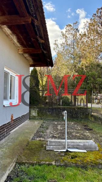 Családi ház Mýtné Ludanyban oldalsó kerttel és gyepfelülettel, kerítéssel körülvéve.