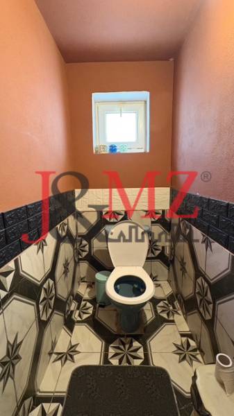 Fürdőszoba egy családi házban, hangsúlyos geometrikus csempével és narancssárga falakkal.