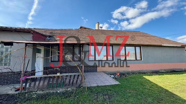 Családi ház Mýtné Ludanyban udvarral, terasszal és szürke homlokzattal.