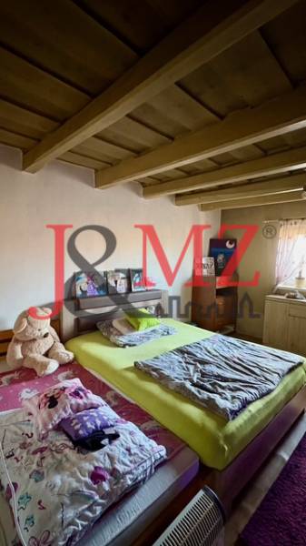 Hálószoba családi házban fa mennyezettel, ággyal és plüssmackóval.