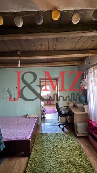 Szoba fa dekoros padlóval, ággyal, íróasztallal és dekoratív gerendákkal a mennyezeten.