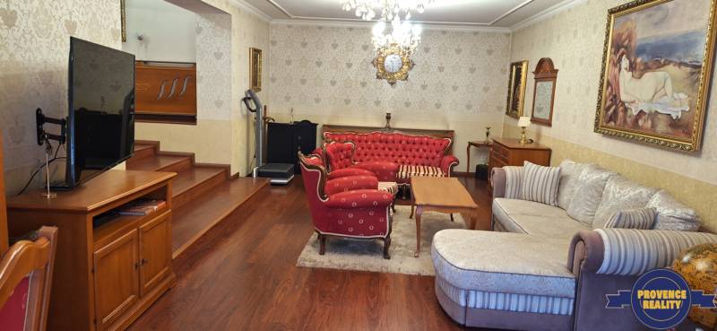 Nappali egy családi házban piros bútorokkal és televízióval, fa dekorációjú padlón.