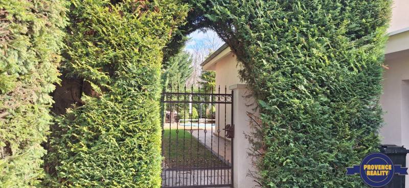 Családi ház kapuval ellátott sövénye Komáromban, a kertbe vezet.