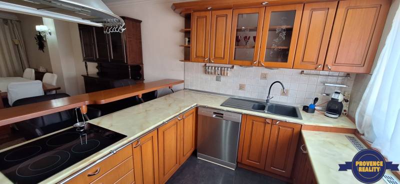 Konyha családi házban fa szekrényekkel és rozsdamentes acél mosogatógéppel.