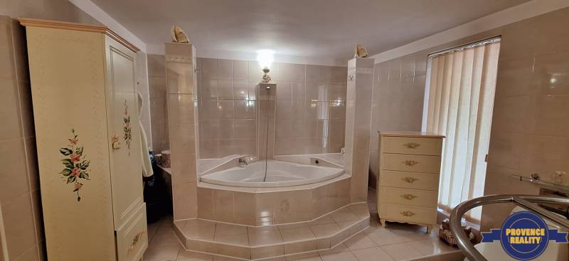 Fürdőszoba családi házban sarokkáddal és díszített bútorokkal.