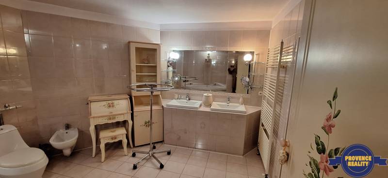 Fürdőszoba családi házban két mosdóval, tükörrel és díszes bútorokkal.