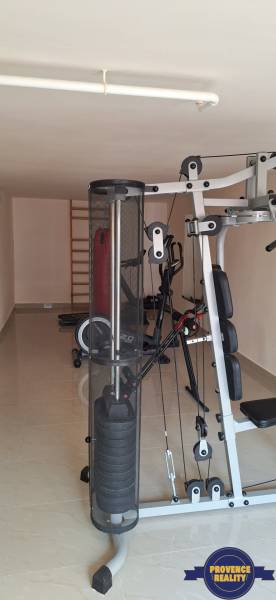 A családi ház edzőterme világos kerámia burkolattal rendelkezik.