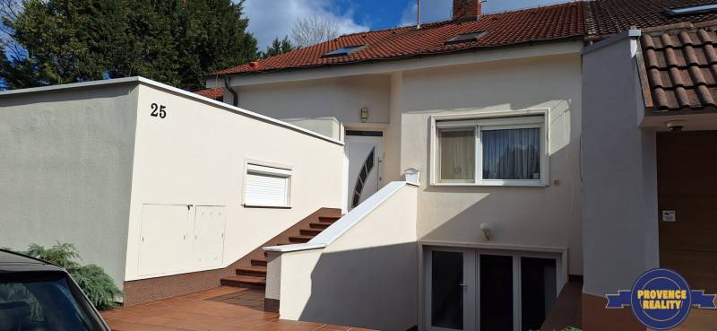 Családi ház Komáromban fehér homlokzattal és piros tetővel.