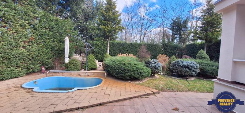 Családi ház Komáromban egy kis medencével és gondozott kerttel, fákkal körülvéve.