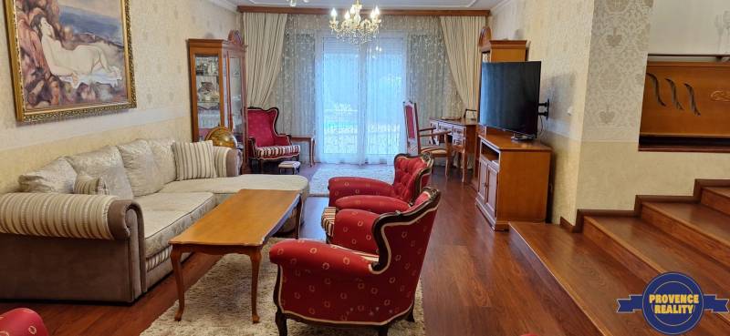 Nappali egy családi házban piros székekkel és fa mintázatú padlóval.