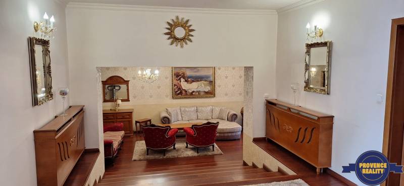 Luxusos családi ház belső tér fa dekorációval, kanapéval és műalkotásokkal a falakon.