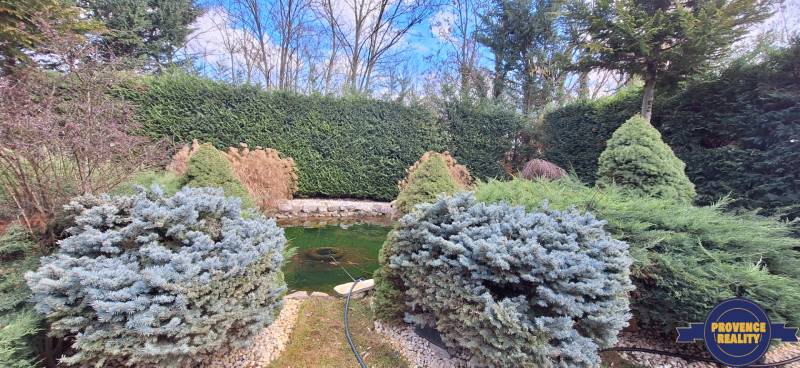 Családi ház Komáromban, kerti tóval és díszcserjékkel a kertben.