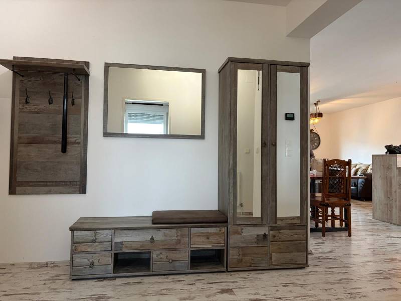 Folyosó egy háromszobás lakásban, fogassal és szekrénnyel, fa dekoros padlóval.