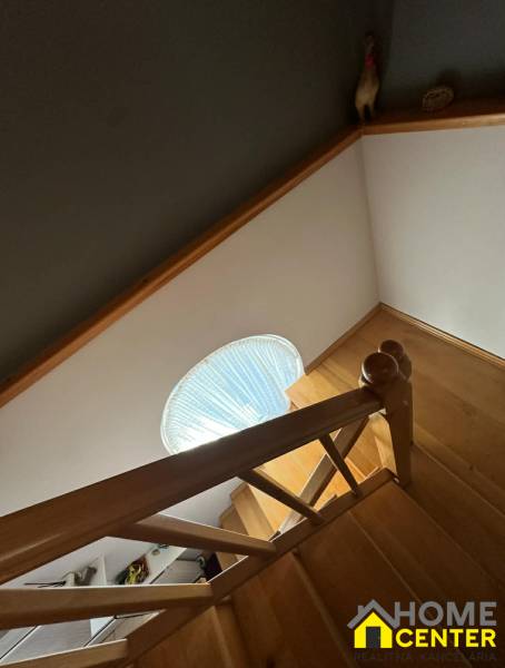 Fa dekorációjú lépcső egy családi házban, lépcsőkorláttal és körablakkal.