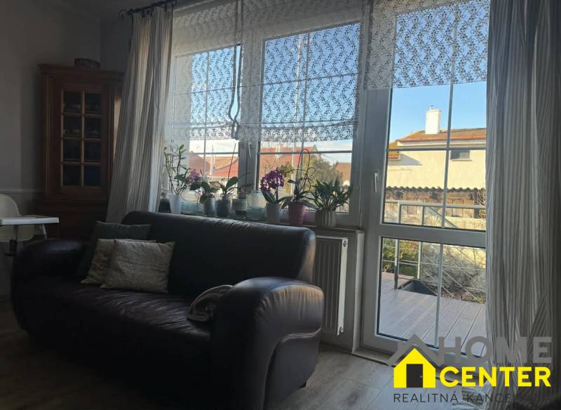 Bőr kanapé és ablak csipkefüggönyökkel a családi házban, fa dekoros padlóval.