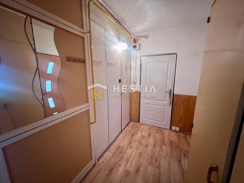 Folyosó egy 3 szobás lakásban fa padlóval, tükörrel és beépített szekrénnyel.