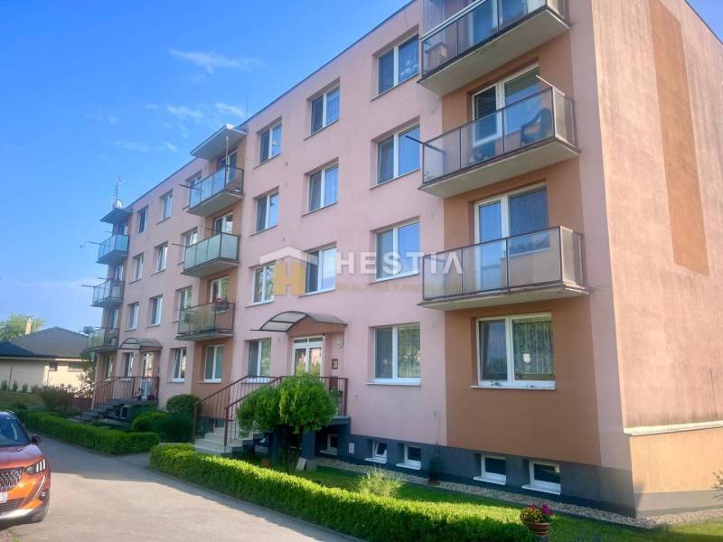 Négyemeletes társasház Moravské Lieskovóban, erkélyekkel és parkolóval az épület előtt.