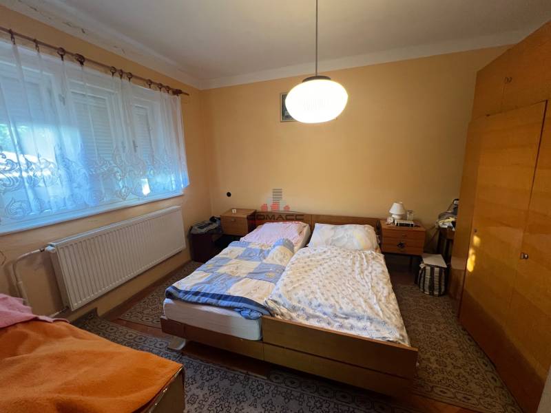 Hálószoba családi házban két ággyal, szekrénnyel és szőnyeggel.