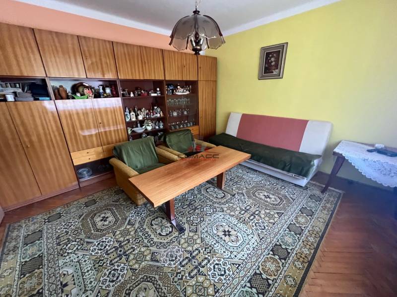 Nappali egy családi házban bútorokkal, szőnyeggel és képpel a falon.