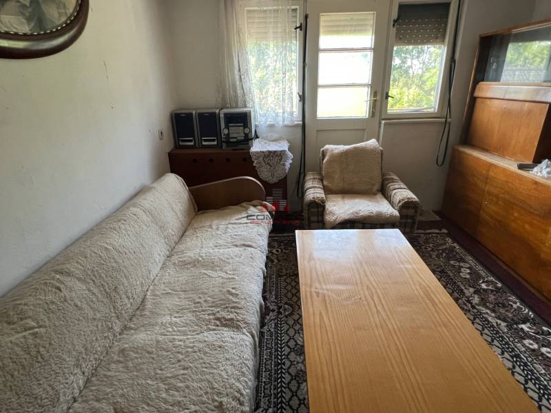 Nappali egy családi házban kanapéval, fotellel és fa bútorokkal.