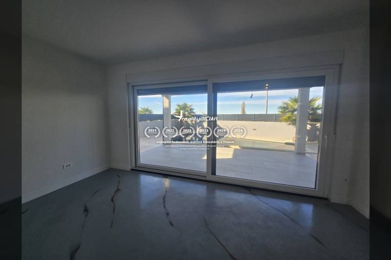 Egy nagy üvegezésű villa belső tere, kilátással a külső medencére.