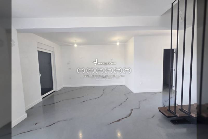 Priestranná miestnosť vo Vile s bielymi stenami a šedou podlahou s dekorom.