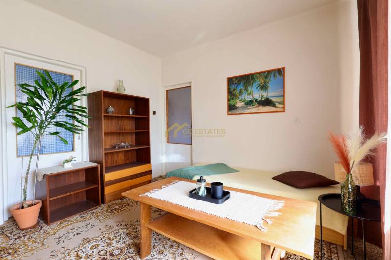 Nappali egy családi házban szőnyegpadlóval, fa bútorokkal és egy tengerparti képpel.