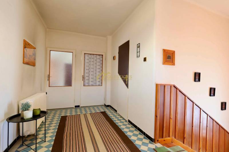 Családi ház mintás burkolattal, fa lépcsőkkel és egyszerű faldekorációval.