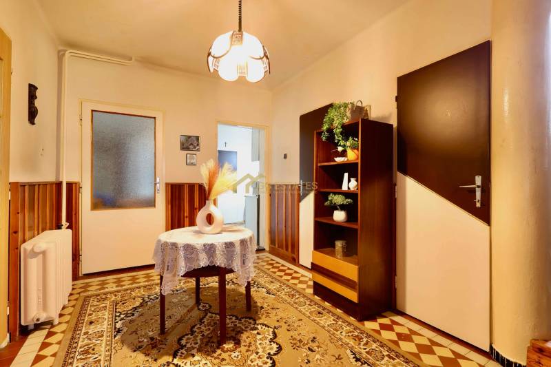 Családi ház belső tere szőnyegpadlóval, a háttérben szekrény és világítás.