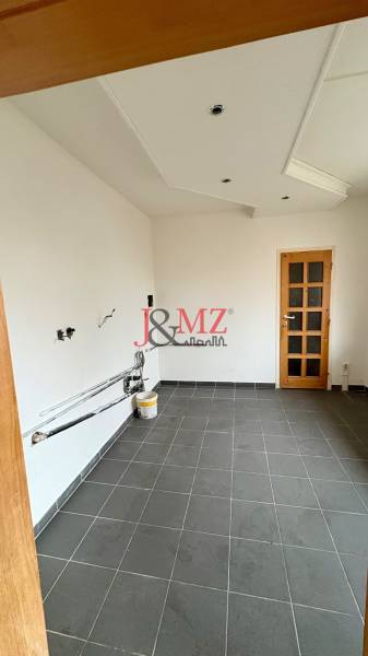 Üres szoba egy kétszobás lakásban, sötét csempézett padló, fehér falak, faajtók.