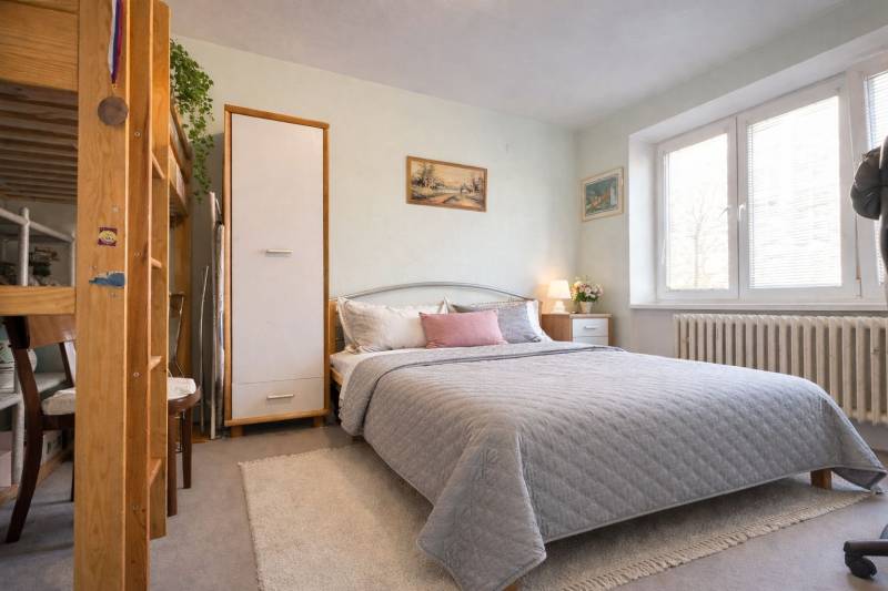 Hálószoba egy kétszobás lakásban nagy ággyal, dekorációkkal és természetes megvilágítással.