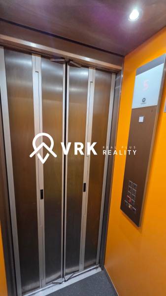 Lift az épületben, gombokkal és egy kijelzővel, amely az ötödik emeletet mutatja.