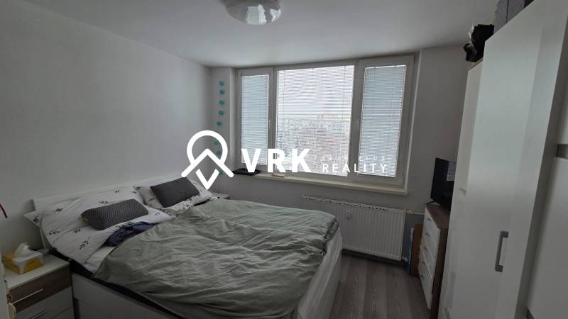 Hálószoba franciaággyal, nagy ablakokkal és fa dekorációjú padlóval egy háromszobás lakásban.