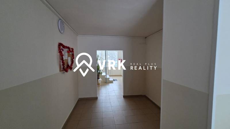 Folyosó fehér falakkal és világos csempével egy háromszobás lakásban.