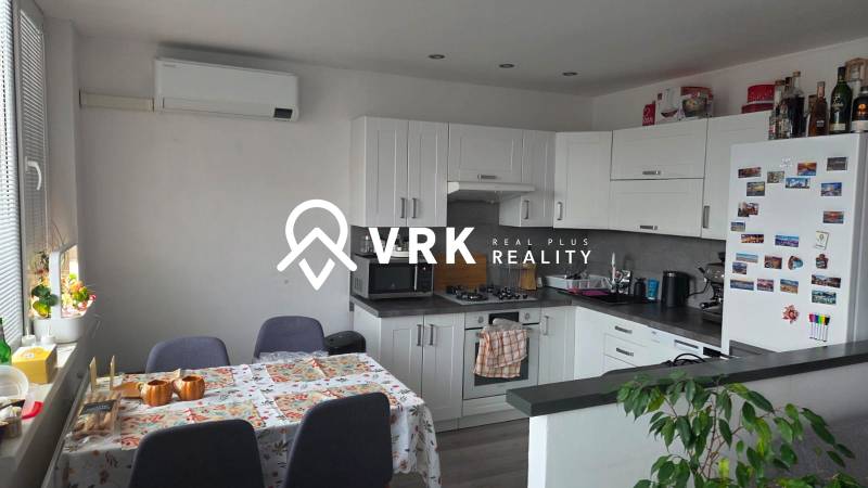 Konyha egy 3 szobás lakásban sarokban elhelyezett konyhabútorral és légkondicionálóval.