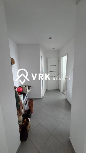 Előszoba egy háromszobás lakásban szürke csempével, cipősszekrény és cipők a földön.