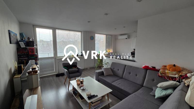 A háromszobás lakás nappalija kanapéval, dohányzóasztallal és fa dekorációjú padlóval.