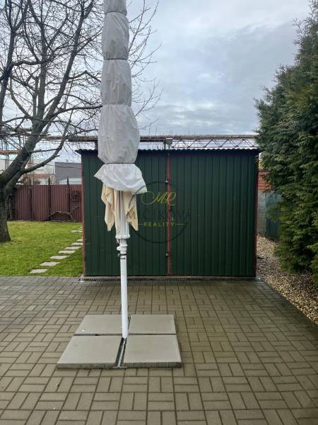 Kertek Alsókrškán, Nyitrán összecsukott napernyővel, szilárd burkolattal és gyepfelülettel.