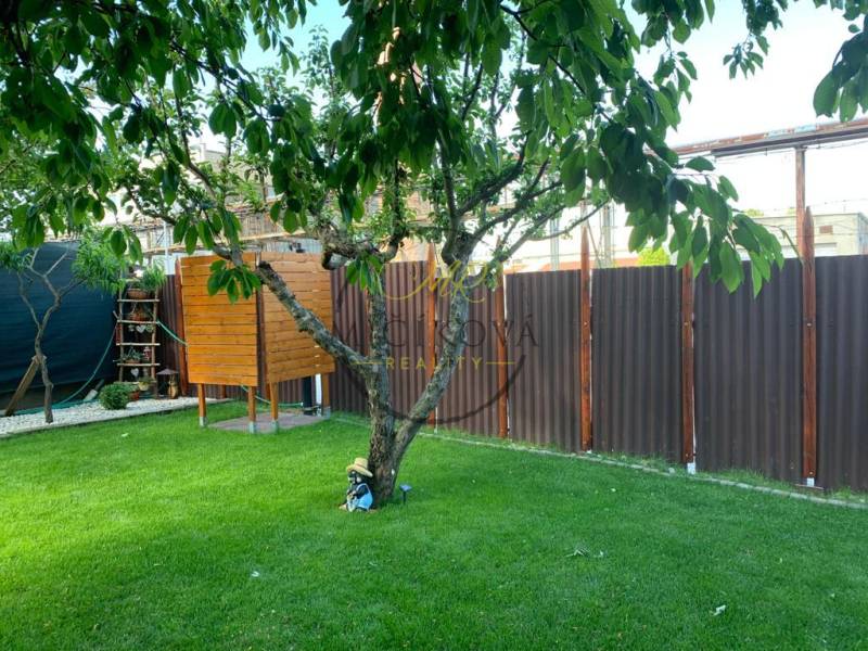 Kertek Dolné Krškany-ban, Nyitra, gyeppel, fával, kis faházzal és kerítéssel.