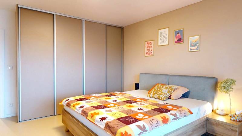 Hálószoba családi házban ággyal, beépített szekrénnyel és dekoratív képekkel a falon.