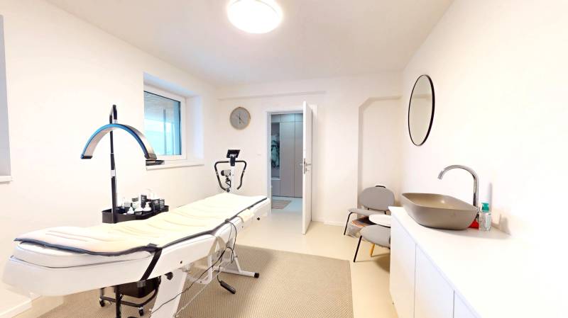 Családi ház belső tere masszázsággyal, mosdókagylóval, tükörrel és székekkel.