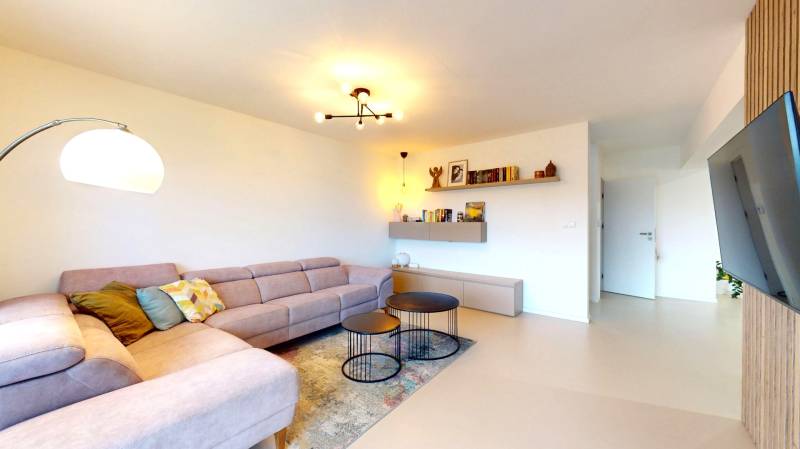 Nappali egy családi házban sarokkanapéval, kerek asztalokkal és fa dekorációjú padlóval.