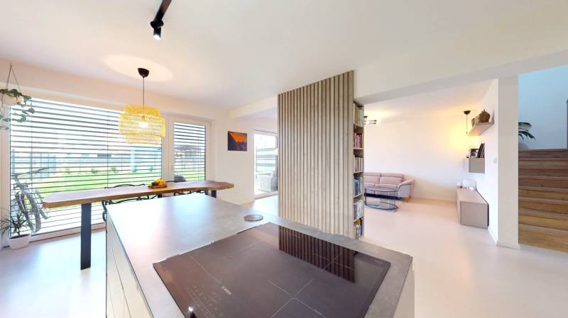 Nyitott belső tér családi házban konyhával, étkezővel és kényelmes nappali sarokkal.