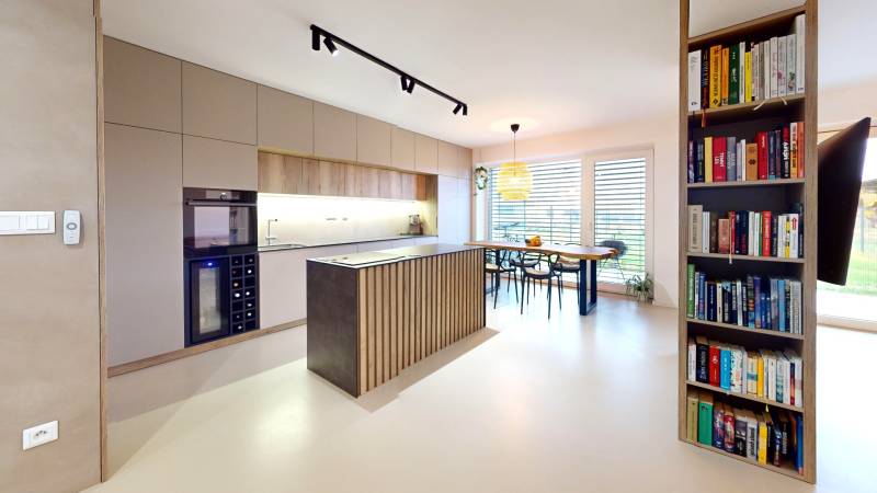 Nyitott konyha étkezőasztallal és könyvespolccal egy családi házban.