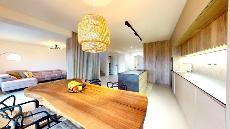 Konyha egy családi házban, faasztallal, kanapéval és modern világítással.