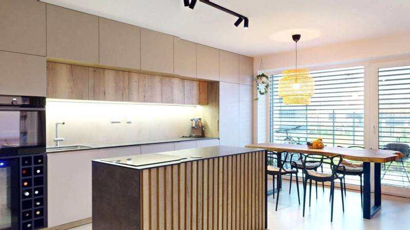 Családi ház konyhája fa dekorációjú bútorokkal és nagy ablakokkal.